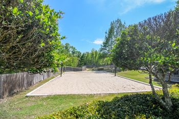 a volleyball court in a park with trees and a fence at Reserve of Jackson Apartment Homes, Jackson, Mississippi